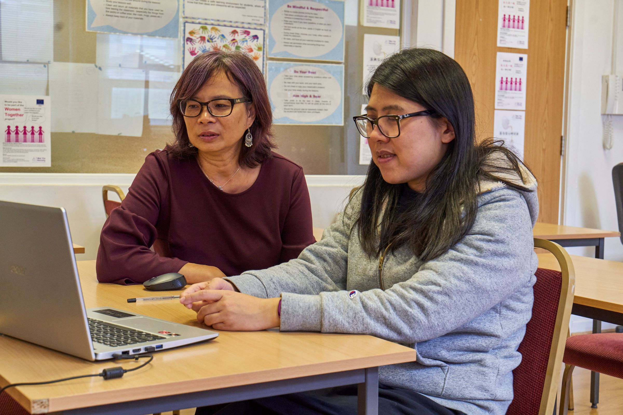 Young girl and woman sitting by a laptop together